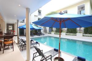 a pool with a blue umbrella and chairs and a table at Adema Boutique Karon in Karon Beach