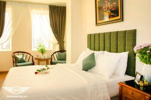 a bedroom with a large white bed with a green headboard at Gia Loc Hotel in Hanoi