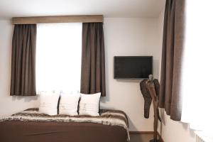 a hotel room with a bed with a window and a tv at Haus Lutt in Ried im Oberinntal