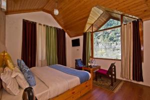 a bedroom with a bed and a large window at The Cedar Cottages & Independent Villa & Kitchenette Fireplace Tandoor & BBQ in Manāli