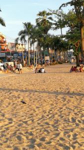 a group of people on a beach with palm trees at Abani Inn in Jomtien Beach