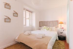 a white bedroom with two beds and a window at Santo António Apartment in Lisbon