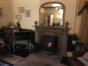 a living room with a fireplace with a television and a mirror at Bank Top Farm B&B Hartington in Buxton +1 photo