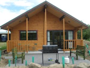 une cabane en rondins avec deux bancs et un grill dans l'établissement Mirabell Chalets, à Alexandra