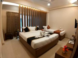 a bedroom with two beds and a large window at GRAND ELEGANT in Chennai