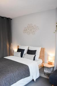 1 dormitorio con 1 cama grande con sábanas y almohadas blancas en La Clef d'Aurélia, en Élancourt