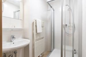 a white bathroom with a shower and a sink at Hotel garni Almenrausch und Edelweiss in Garmisch-Partenkirchen