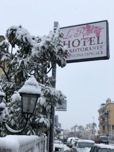 een straatbord en een straatlicht bedekt met sneeuw bij Hotel Le Rose in Tivoli Terme