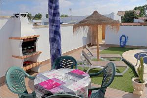 un patio con mesa, sillas y chimenea en Chalet Muelle Pesquero 65, en Conil de la Frontera