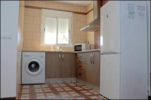 a kitchen with a washing machine and a refrigerator at Chalet Muelle Pesquero 65 in Conil de la Frontera