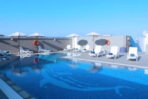 a swimming pool with chairs and umbrellas at Al Diar Sawa Hotel Apartments in Abu Dhabi