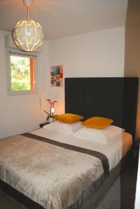 a bedroom with a bed with orange pillows and a window at APPART CLIMATISE / TERRASSE A 2 MIN DE LA PLAGE in LʼÎle-Rousse