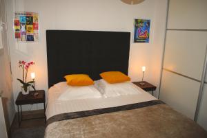 a bedroom with a large bed with two orange pillows at APPART CLIMATISE / TERRASSE A 2 MIN DE LA PLAGE in LʼÎle-Rousse