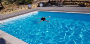 a man swimming in a blue swimming pool at Bed House Floristella in Valguarnera Caropepe