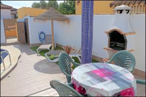 eine Terrasse mit einem Tisch, Stühlen und einem Kamin in der Unterkunft Chalet Muelle Pesquero 66 in Conil de la Frontera