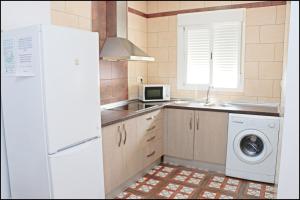 eine Küche mit einem weißen Kühlschrank und einer Waschmaschine in der Unterkunft Chalet Muelle Pesquero 66 in Conil de la Frontera
