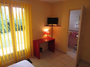 a room with a desk with a lamp and a television at Locatlantique in Aytré