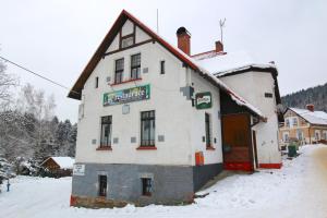 a building with a sign on it in the snow at Penzion Paseky U Zapadlych vlastencu in Paseky nad Jizerou