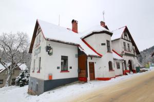 a white building with snow on it on a street at Penzion Paseky U Zapadlych vlastencu in Paseky nad Jizerou