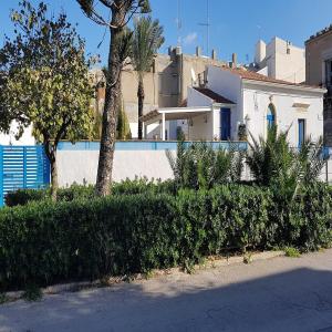 ein weißes Haus mit einem Zaun mit Bäumen und Sträuchern in der Unterkunft VILLA RISORGIMENTO in centro sul corso principale in Scoglitti