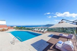 a swimming pool with lounge chairs and an umbrella at Alivia Lefkas Luxury Villas in Apolpaina