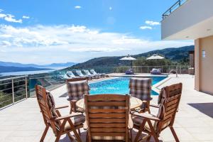 un patio con mesa y sillas y una piscina en Alivia Lefkas Luxury Villas en Apolpaina