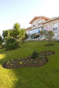 a house with a flower bed in the yard at Hotel Begoña Park in Gijón