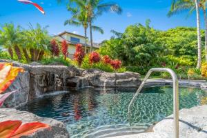 a swimming pool with a waterfall and a rock wall at Mauna Lani Palm Villas in Waikoloa