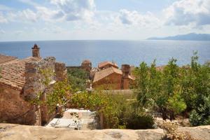 a group of buildings with the ocean in the background at Old Traditional House in the Castle of Monenvasia in Monemvasia
