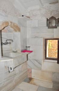 uma casa de banho com um lavatório e uma janela em Old Traditional House in the Castle of Monenvasia em Monemvasia