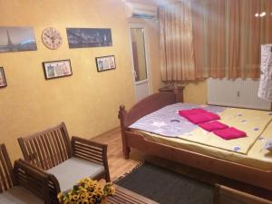 een slaapkamer met een bed en een stoel en een klok bij Apartament Sonia ARHB 3 camere in Boekarest