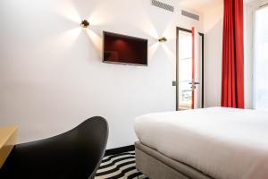 1 dormitorio con 1 cama y TV en la pared en Hotel Pilime en París