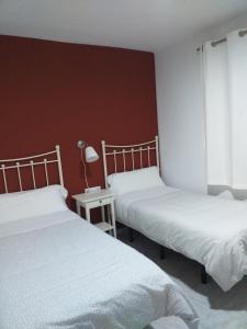 a bedroom with two beds and two lamps at Hostal Monteluna in Rociana