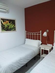 a bedroom with a white bed and white walls at Hostal Monteluna in Rociana