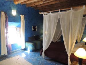 een slaapkamer met een bed en gordijnen in een kamer bij Dar Qamar in Agdz