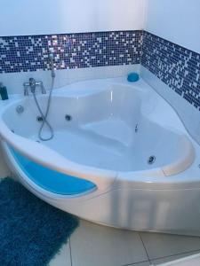 La salle de bains est pourvue d'une baignoire blanche et d'un mur en carrelage. dans l'établissement MOTEL 24H, à Aversa