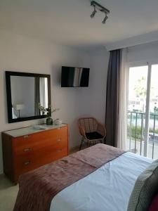 a bedroom with a bed and a dresser and a mirror at Club La Costa World Resort in Fuengirola