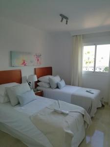 two beds in a white room with a window at Club La Costa World Resort in Fuengirola