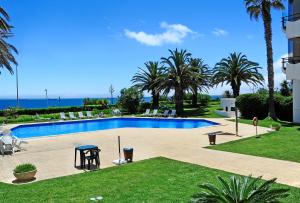 uma grande piscina com palmeiras e o oceano em Sunset Balcony in Estoril - Checkinhome em Estoril