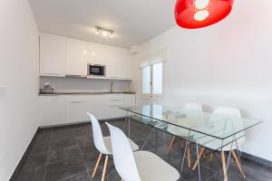 a kitchen with a glass table and white chairs at Apartamentos Gama in Cala Galdana