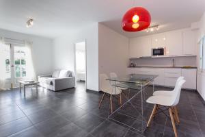a kitchen and living room with a glass table and chairs at Apartamentos Gama in Cala Galdana