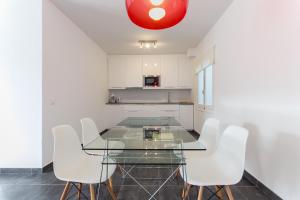 a dining room with a glass table and white chairs at Apartamentos Gama in Cala Galdana