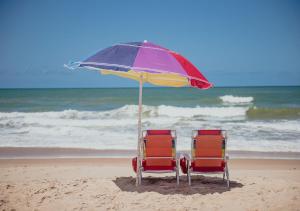 twee stoelen onder een parasol op het strand bij Flat Guarajuba Beira da Praia pé na areia in Guarajuba