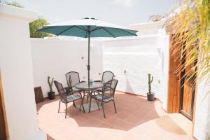 eine Terrasse mit einem Tisch, Stühlen und einem Sonnenschirm in der Unterkunft El Cerro de la Luna in Arona