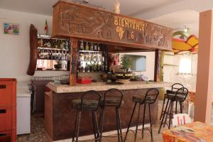 een bar met vier krukken aan een bar met flessen bij Africa 6 Plage in Somone