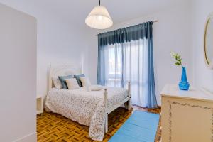 a white bedroom with a bed with blue pillows at Casa da Esquina - Faro city center in Faro