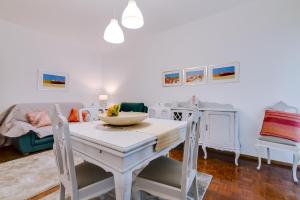uma sala de jantar branca com uma mesa e um sofá em Casa da Esquina - Faro city center em Faro