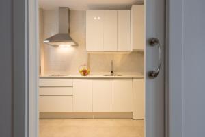 Una cocina con gabinetes blancos y un fregadero. en San Jerónimo 17 Suites, en Granada