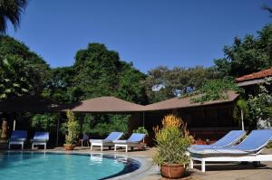 a swimming pool with lounge chairs and an umbrella at La Mada Hotel in Nairobi