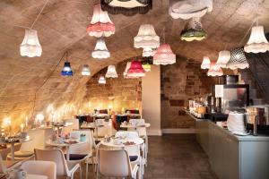 un restaurant avec des tables blanches, des chaises et des lumières dans l'établissement Hôtel Marais Hôme, à Paris